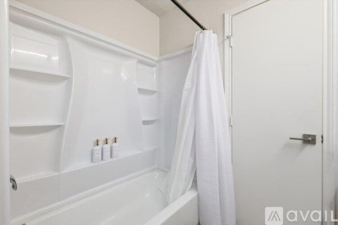 A bedroom with a white bed and a ceiling fan.