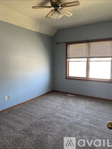 A room with a ceiling fan and a window with blinds.