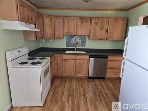 A kitchen with a white stove and wooden cabinets.