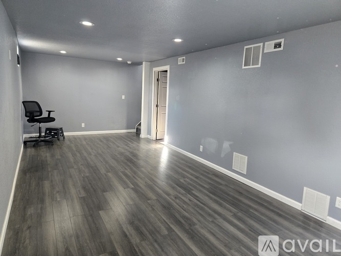 A spacious room with a wooden floor and a black office chair.