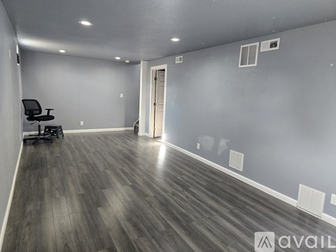 A spacious room with a wooden floor and a black office chair.