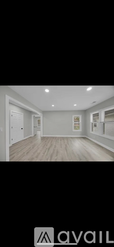 A spacious room with wooden flooring and white walls.