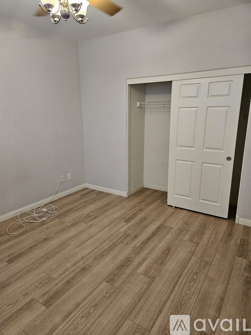 A room with a white door and wooden flooring.