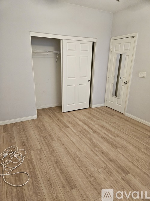 A room with a white door and a wooden floor.