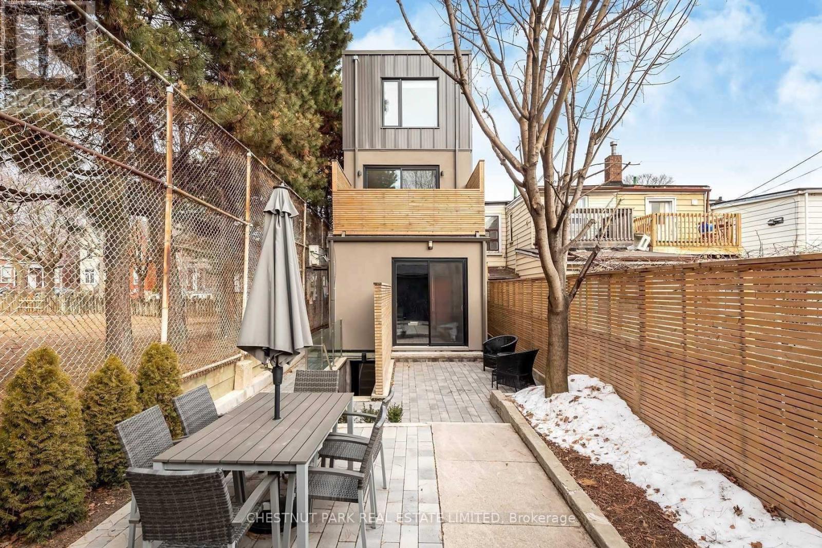 A patio with a table and chairs is surrounded by a fence and a building.