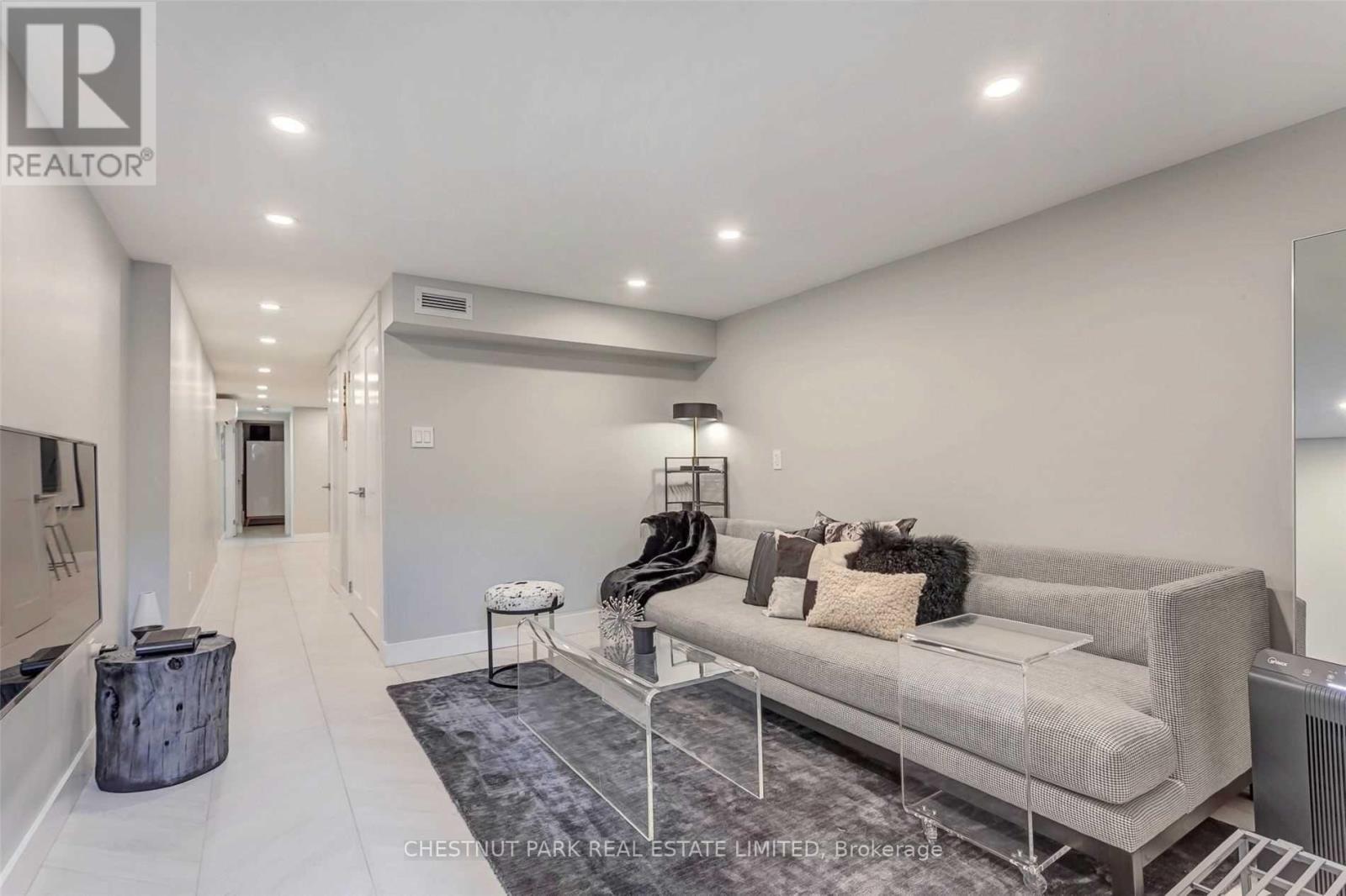 A spacious living room with a grey sofa and a rug.