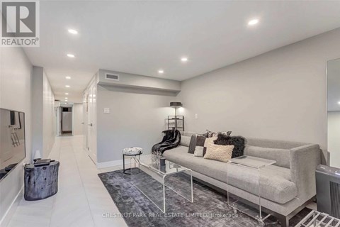 A spacious living room with a grey sofa and a rug.