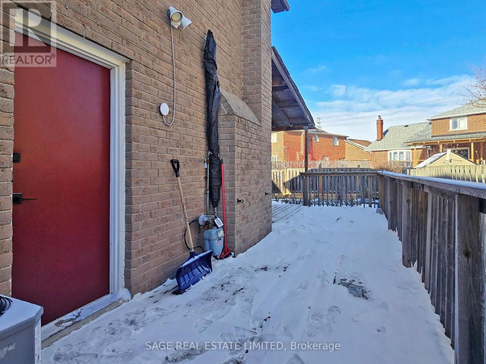 A red door is on the left side of a brick building.