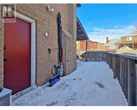 A red door is on the left side of a brick building.