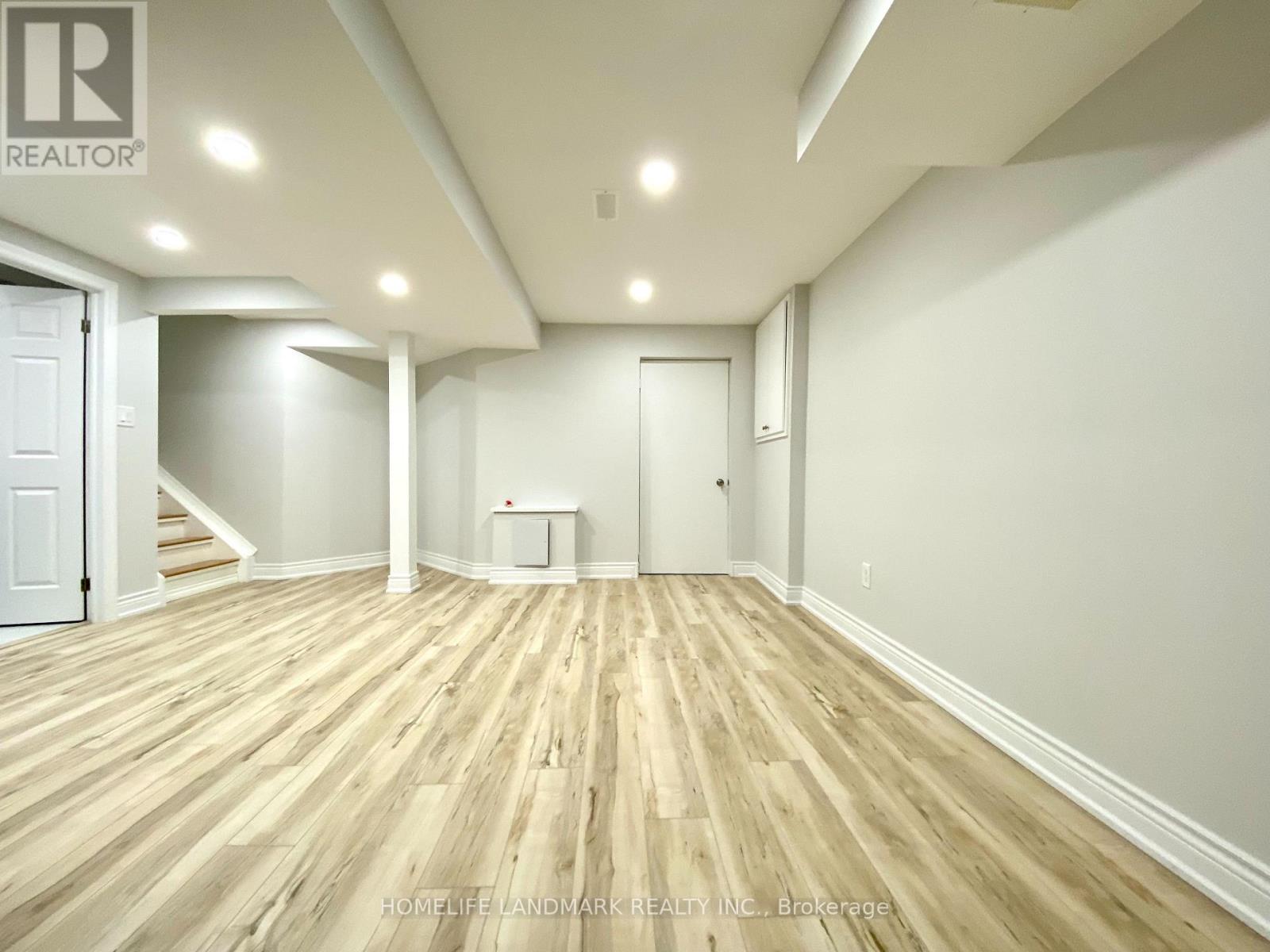 A spacious room with wooden flooring and white walls.
