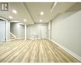 A spacious room with wooden flooring and white walls.