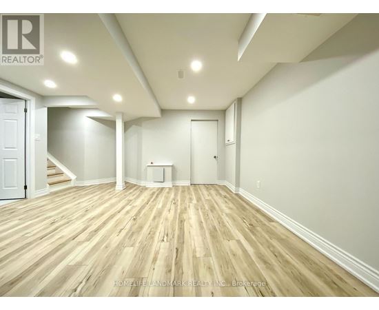 A spacious room with wooden flooring and white walls.