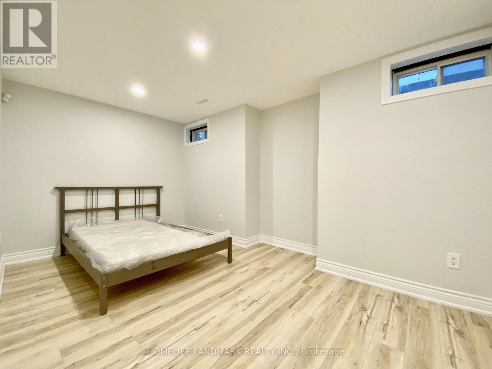 A bedroom with a bed, wooden floors, and a window.