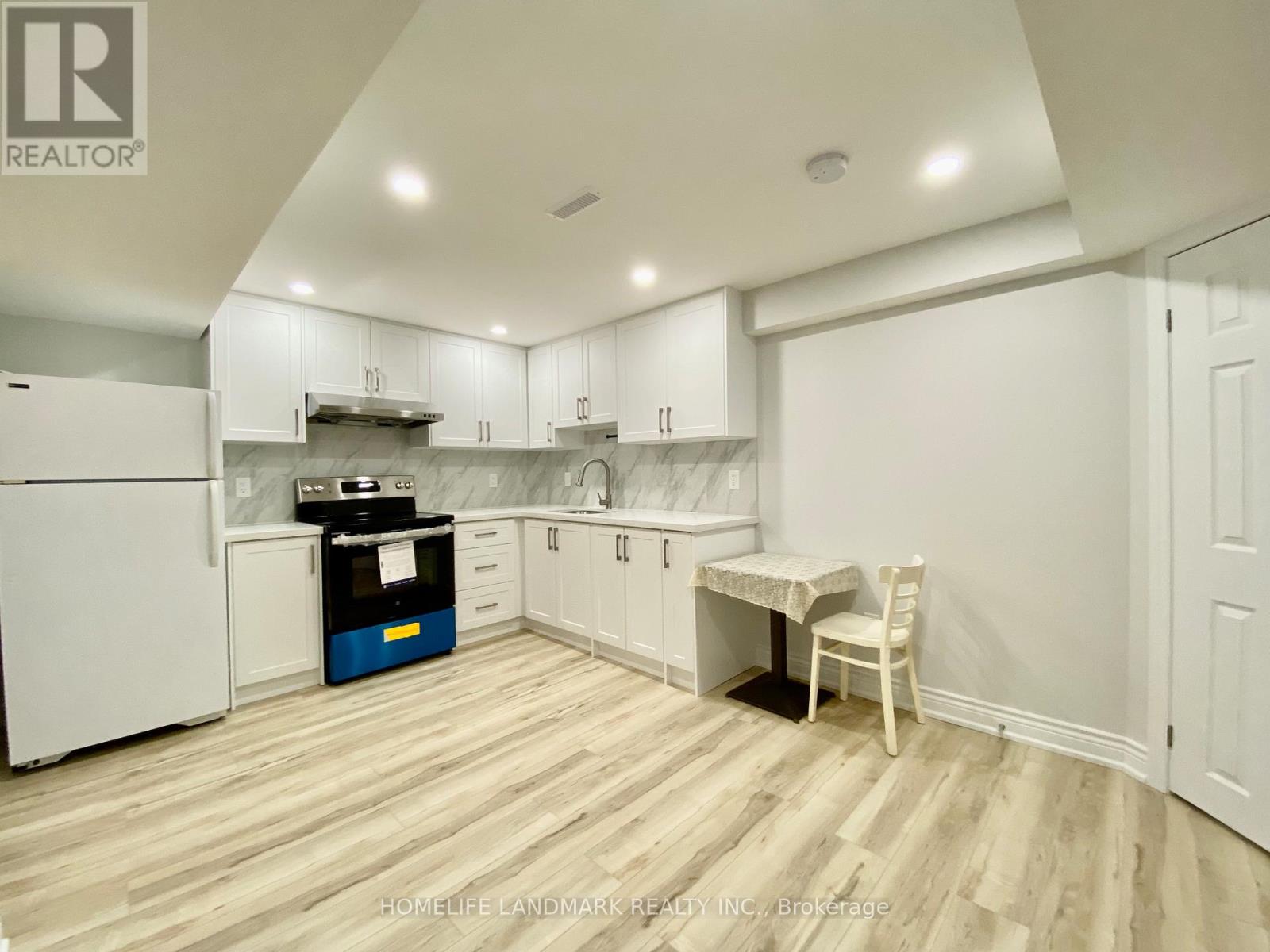 A kitchen with white cabinets and a wooden floor.