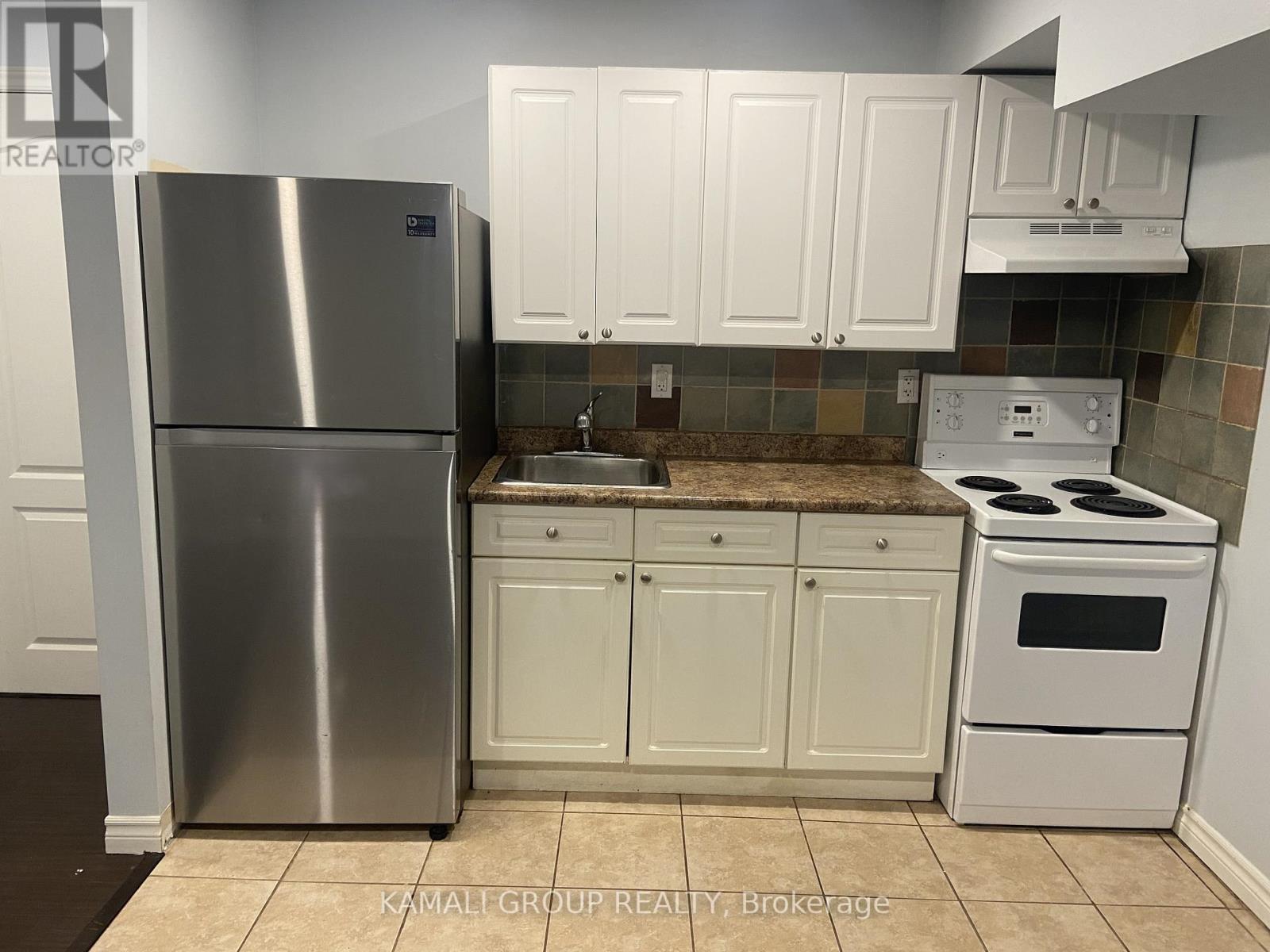 A kitchen with a stainless steel refrigerator and white cabinets.