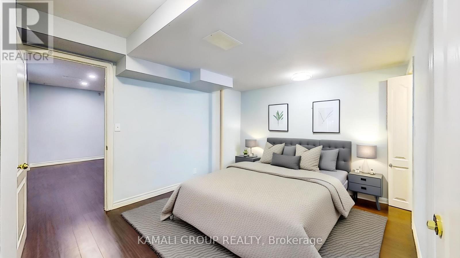 A bedroom with a bed, nightstands, and pictures on the wall.