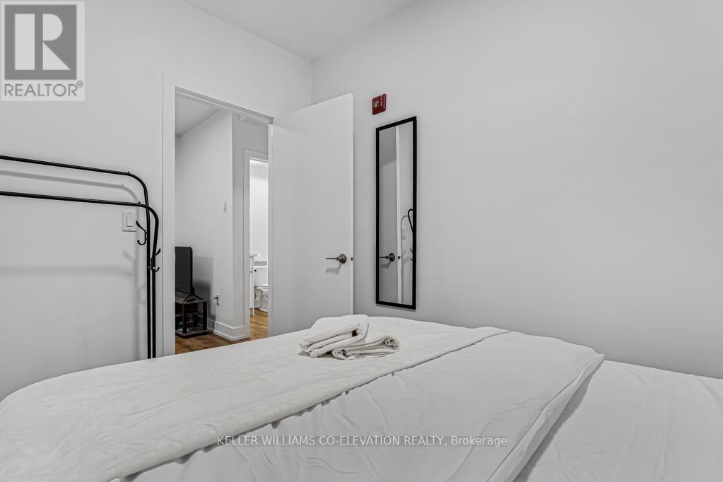 A bedroom with a bed, a chair, and a mirror on the wall.