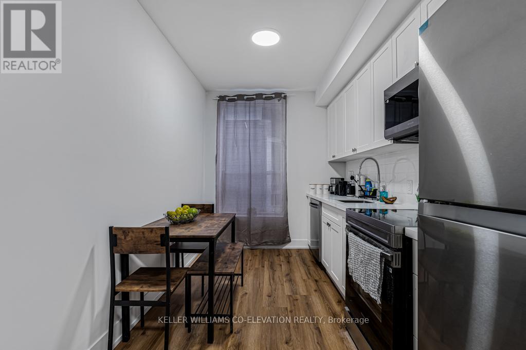 A kitchen with a table and chairs in front of a stainless steel refrigerator.