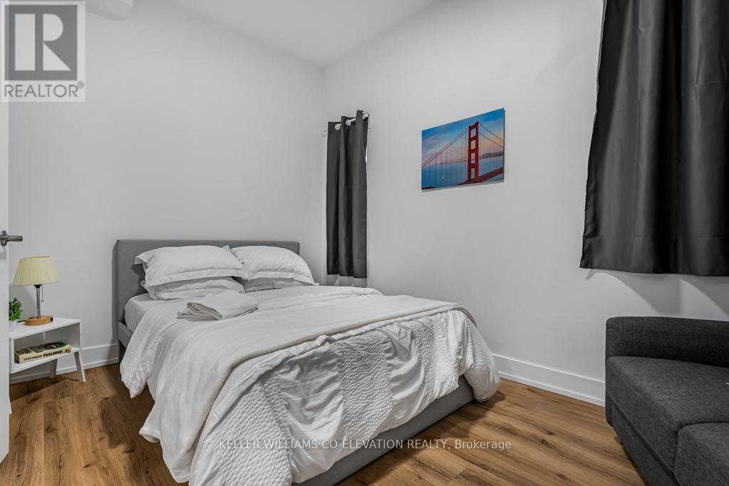 A bedroom with a large bed and a painting of the Golden Gate Bridge on the wall.