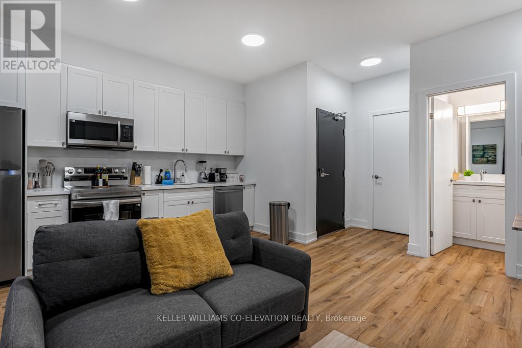 A modern kitchen with a grey couch and a yellow pillow.