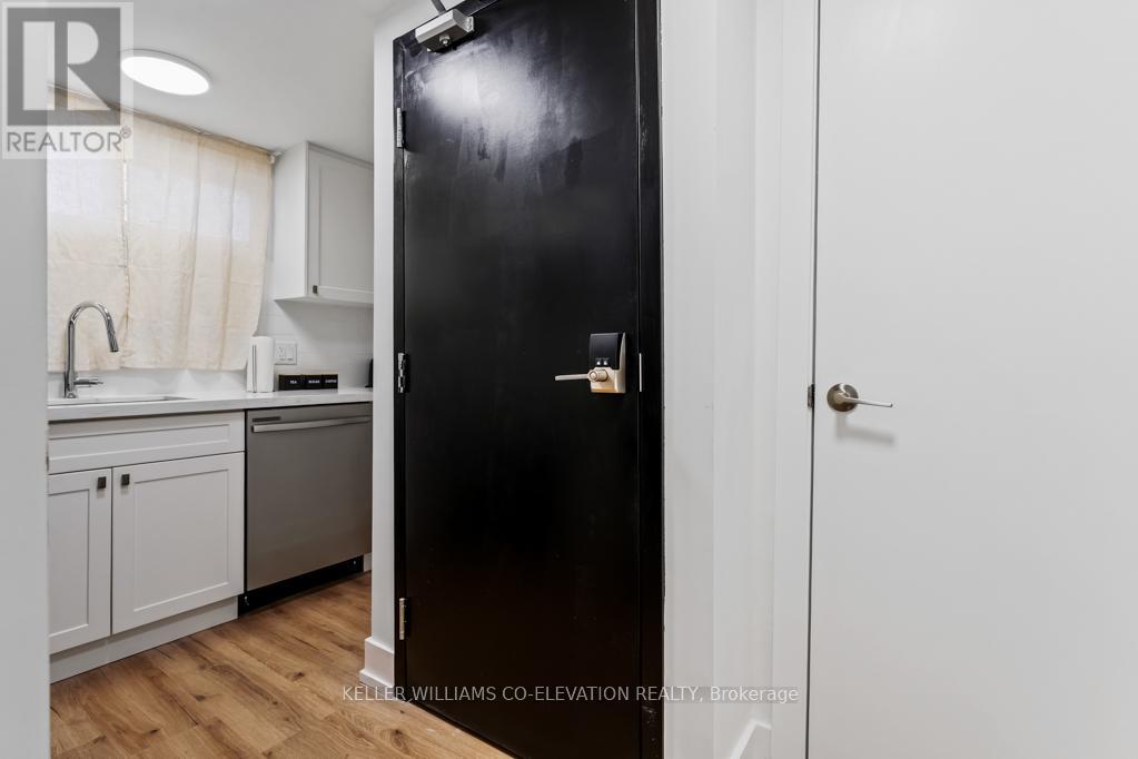 A black fridge in a kitchen with white cabinets.