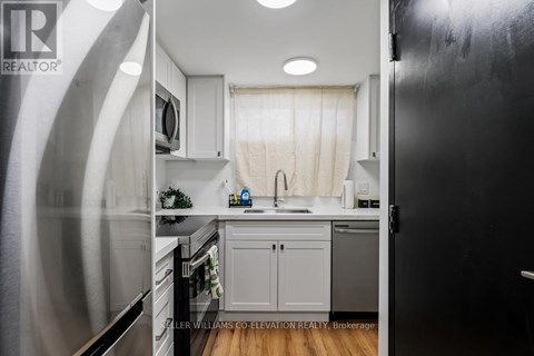 A kitchen with a black refrigerator and white cabinets.