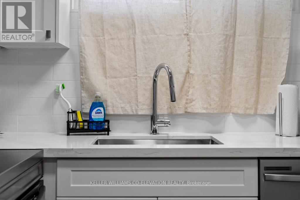 A kitchen sink with a faucet and a toothbrush holder with toothpaste on it.