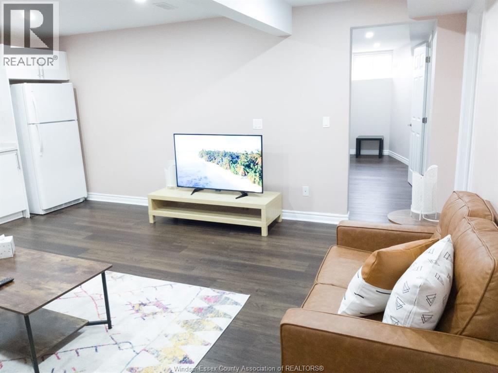 A living room with a brown couch and a television on a wooden stand.