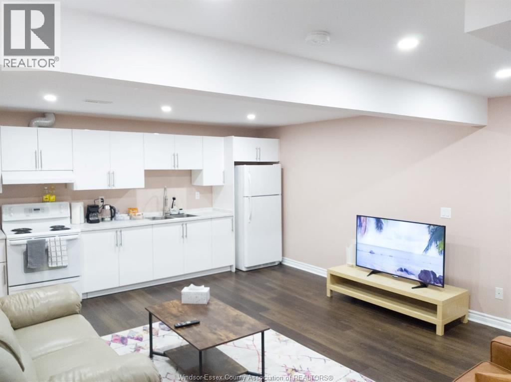 A modern kitchen with white cabinets and a wooden floor.