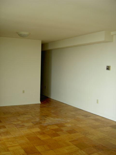 an empty living room with a wooden floor and white walls