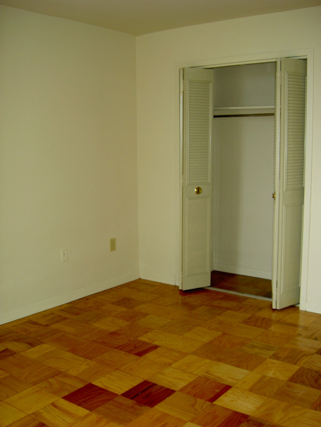 an empty room with a wooden floor and a closet