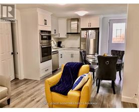 A yellow chair with a blue pillow is in the foreground of a kitchen.