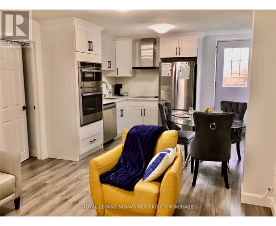 A yellow chair with a blue pillow is in the foreground of a kitchen.