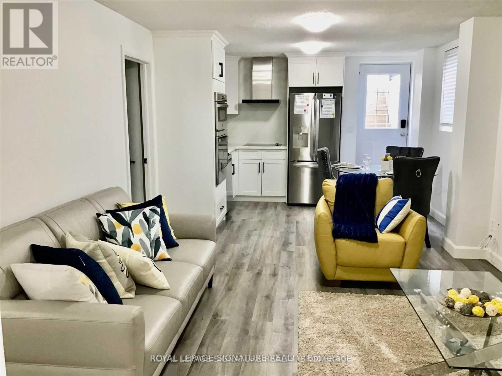 A living room with a yellow chair and a glass table.