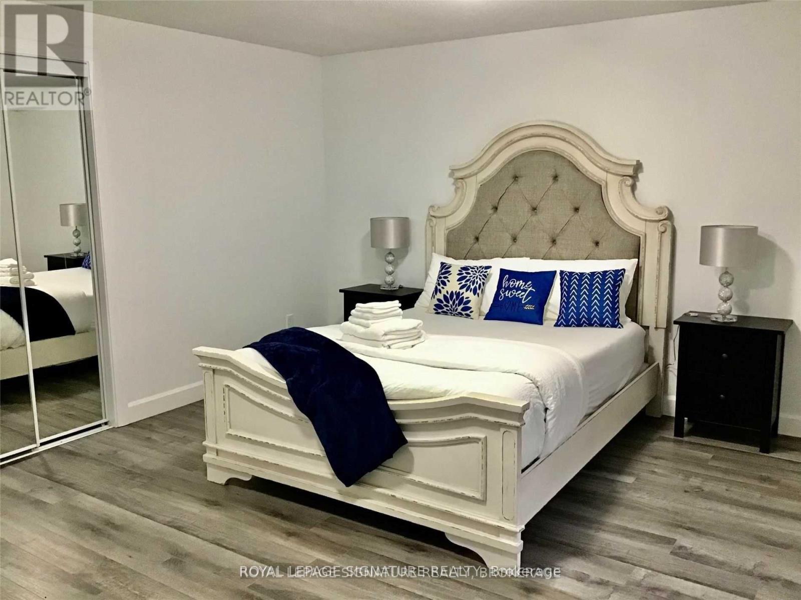 A bedroom with a white bed and blue pillows.