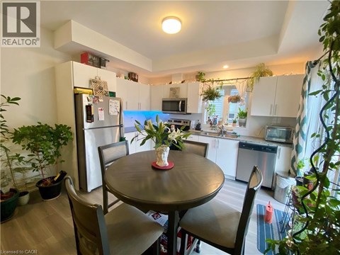 A kitchen with a table and chairs in the foreground and a refrigerator in the background.