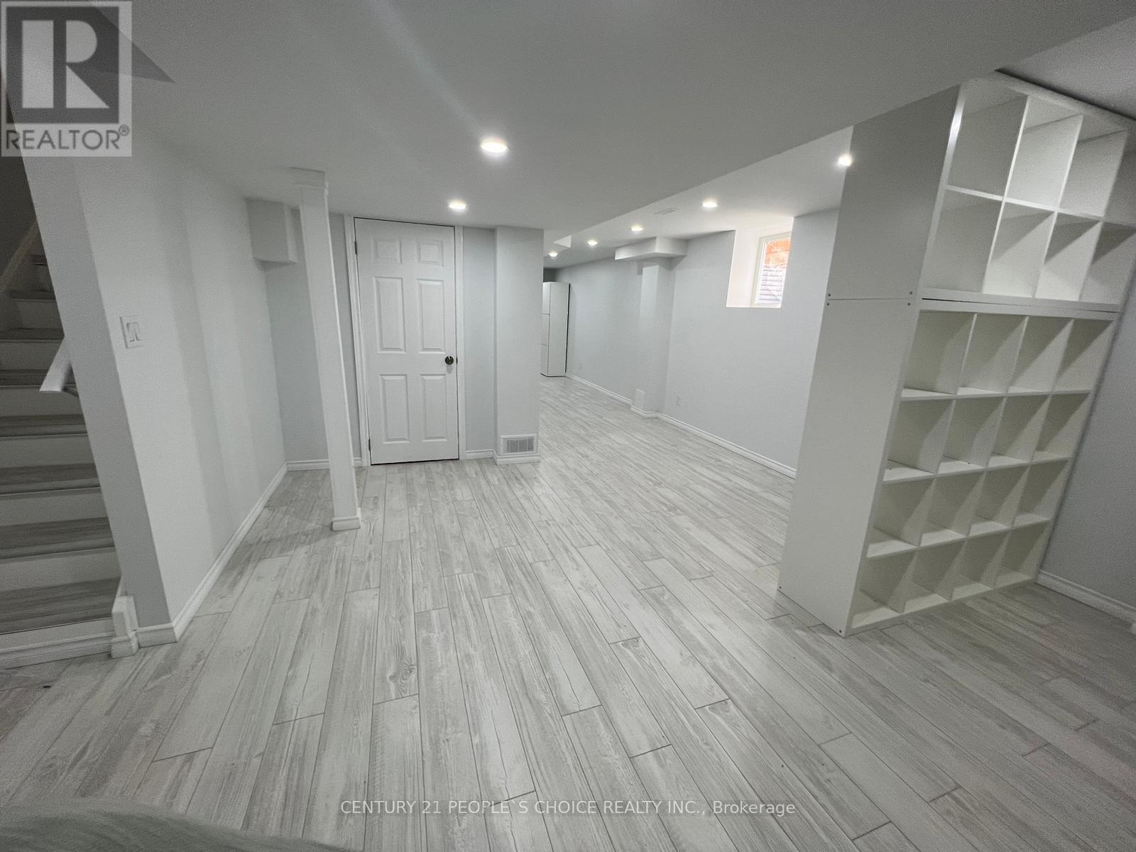 A spacious room with wooden flooring and white walls.