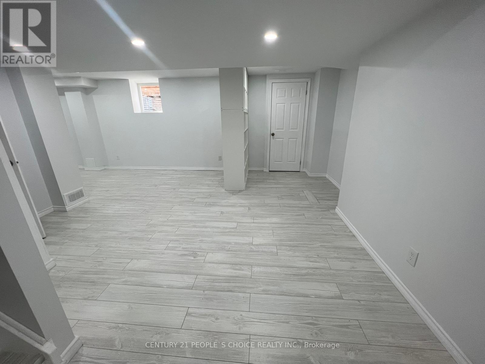 A spacious room with a wooden floor and white walls.