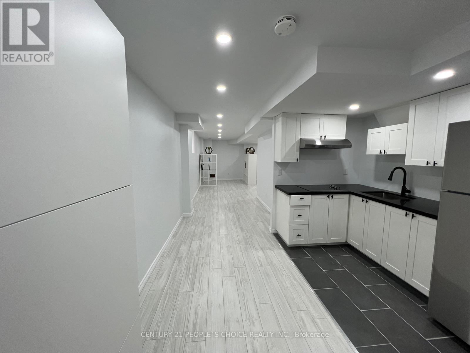 A modern kitchen with white cabinets and black countertops.