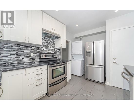 A kitchen with white cabinets and a stone backsplash.