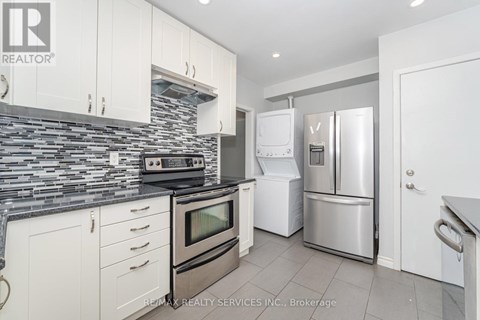 A kitchen with white cabinets and a stone backsplash.
