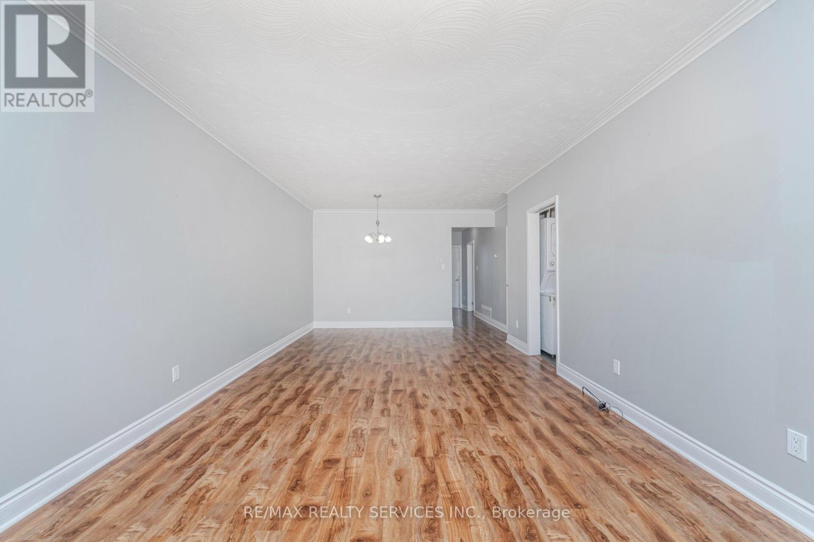 A spacious room with wooden flooring and white walls.
