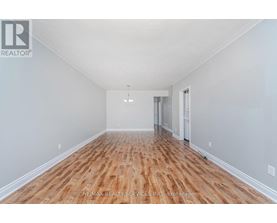A spacious room with wooden flooring and white walls.