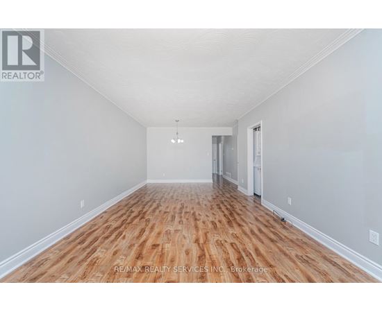 A spacious room with wooden flooring and white walls.