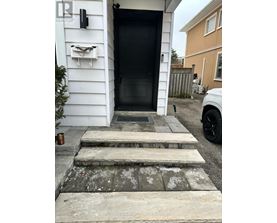 A black door is on the left side of a white house.