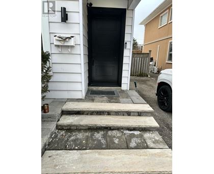A black door is on the left side of a white house.