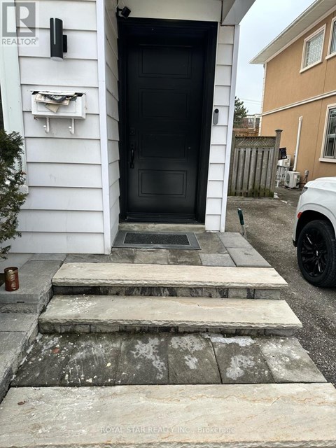 A black door is on the left side of a white house.