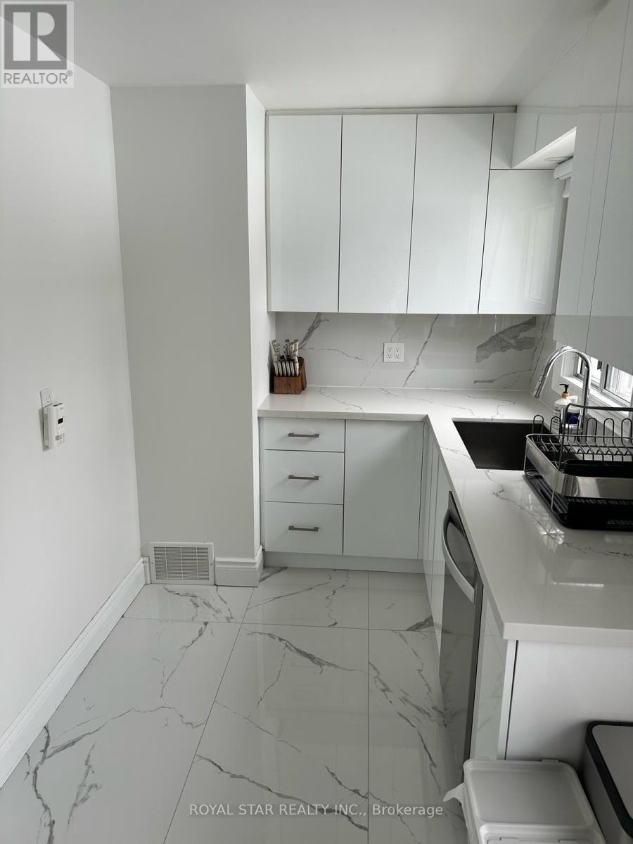 A kitchen with white cabinets and marble countertops.