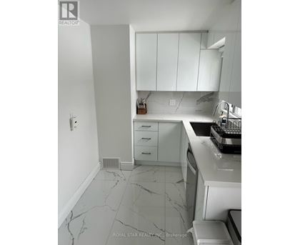 A kitchen with white cabinets and marble countertops.