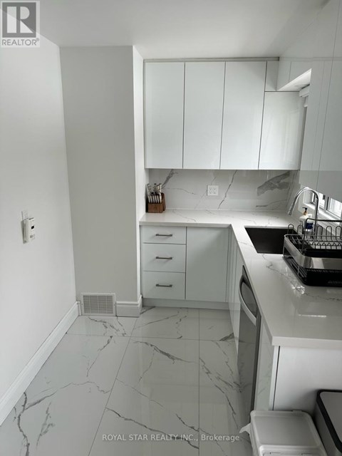 A kitchen with white cabinets and marble countertops.